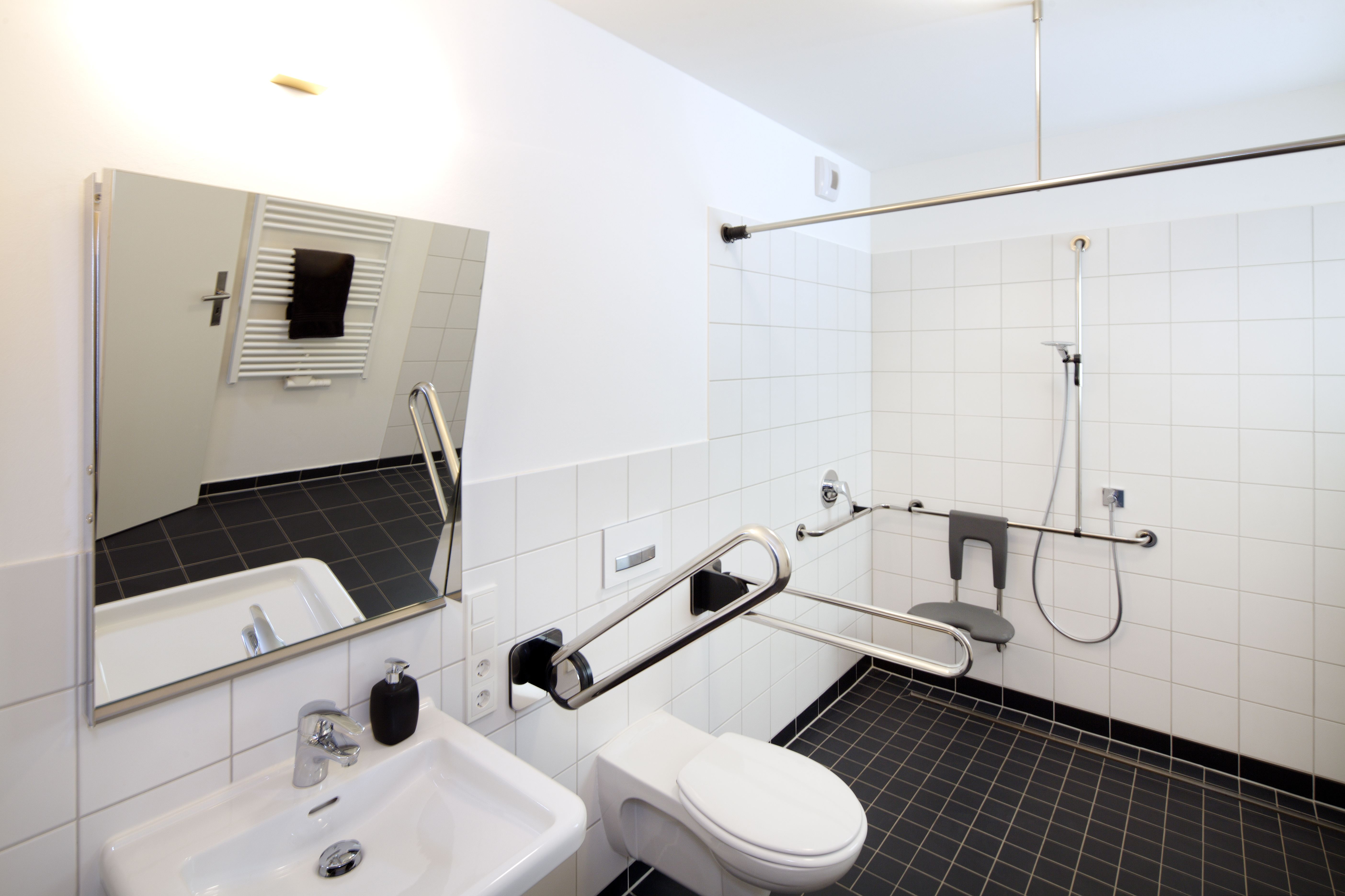 Altersgerechtes Bad mit klappbaren Haltegriffen am WC und bodengleicher Dusche mit Klappsitz