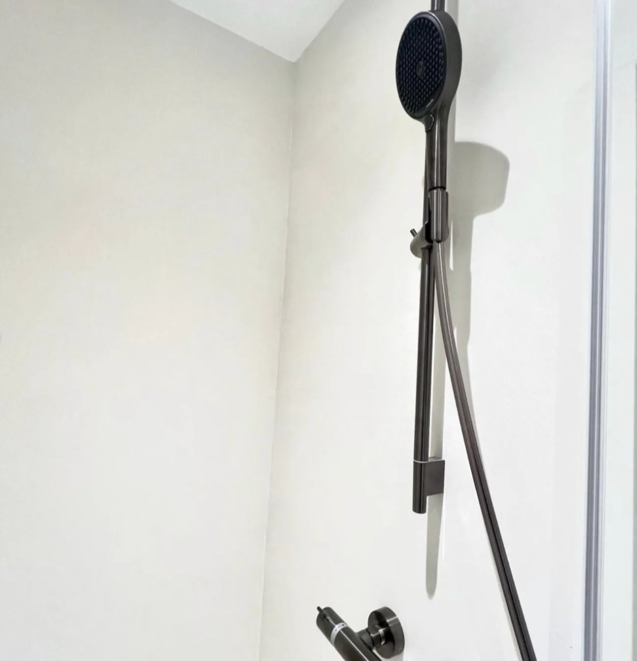 Fugenlose Duschwand ohne eine einzige Fuge, Brausestange und Thermostat in Schwarz
